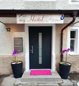 福森my Hostel Füssen的前面有粉红色地毯的黑色前门