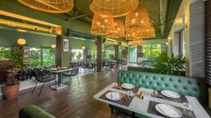 钦奈Green Meadows Resort的餐厅设有绿色的沙发和桌椅