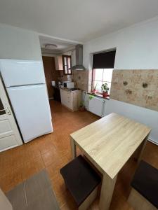 康斯坦察Villa Dumbrava Rosie的厨房配有木桌和白色冰箱。