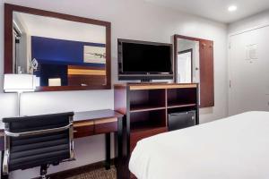 皇后区Avion Inn Near LGA Airport, Ascend Hotel Collection的一间卧室配有一张床和一张书桌及电视