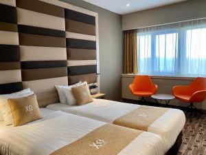 阿姆斯特丹XO酒店蓝塔店的酒店客房,配有两张床和橙色椅子