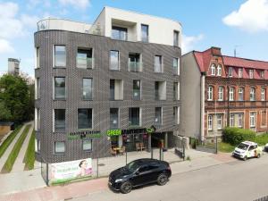 霍茹夫Green Apartments Katowice Chorzów的停在大楼前的一辆黑色汽车