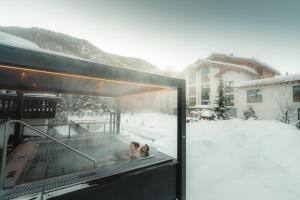 采尔马特Alpen Resort & Spa的两名儿童在雪地的热水浴池玩耍