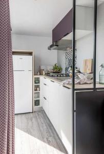 TintignyChênefleur的厨房配有白色橱柜和黑色冰箱。