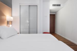 洛格罗尼奥Eurostars Marqués de Vallejo的一间白色卧室,配有两张床和一个衣柜