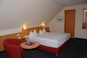 Luhden阿尔特学派酒店的酒店客房,配有一张床和一张红色椅子
