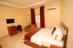 MakurduRoom in Lodge - Lois Hotels Ltd Makurdi的一间卧室配有一张床、一张书桌和一台电视
