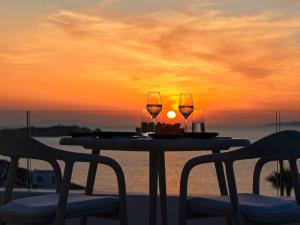 米克诺斯城Mykonos Earth Suites的一张桌子,两杯葡萄酒和两把椅子