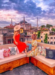 伊斯坦布尔Henna Hotel Istanbul的两名妇女坐在俯瞰着城市的阳台的长凳上
