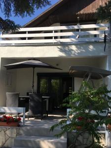 鲍洛通维拉戈什Nefelejcs Apartman的庭院配有遮阳伞和桌椅。