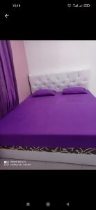 塞里布群岛Homestay safari pulau tidung的一张带紫色床单和紫色枕头的床