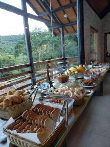 卡曼杜卡亚Pousada Cabana na Floresta - Monte Verde的一张长桌,上面有面包和一篮子的食物