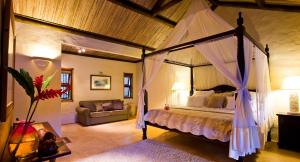 沙马雷勒哈马独家洛奇酒店的一间卧室配有天蓬床和沙发