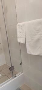 AksaySulo Aksai Hotel的玻璃门淋浴和毛巾