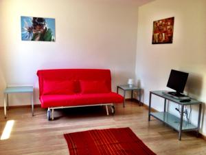 弗留利地区奇维达莱Casa Romea的客厅配有红色沙发和笔记本电脑