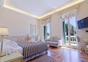 圣雷莫巴黎圣雷莫酒店的一间卧室配有一张床、一把椅子和窗户。