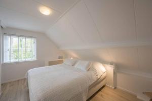 斯霍尔Sous les Dunes的白色的卧室设有床和窗户