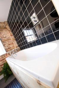 赫特福德多格安德威舍旅馆的浴室铺有黑色瓷砖,配有白色浴缸。