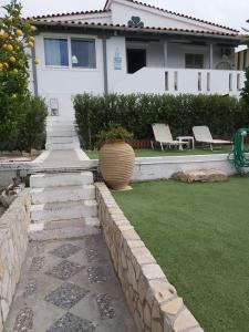 索瓦拉Elia Villa - Aegina, Souvala的一座带花园的房子,花园内配有两把椅子和一个花瓶