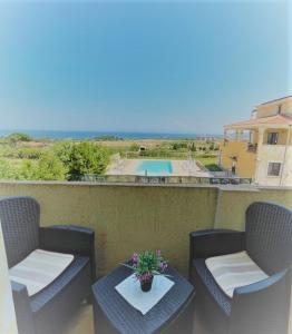 瓦雷多利亚Appartamenti Abbaidda的一个带两把椅子和一张桌子的阳台以及一个游泳池