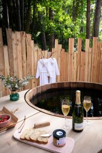 讷沙泰勒阿尔代洛Bain de forêt - Lodges Cosy & Spa的一张桌子,上面放有两杯葡萄酒和一瓶香槟
