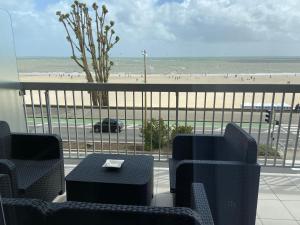 拉波勒Le Cheval Bleu的一个带桌椅的阳台和一个海滩