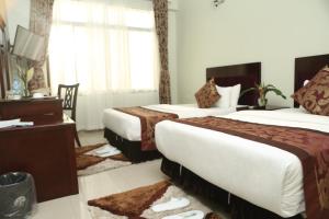 姆万扎Adden Palace Hotel & Conference Centre的酒店客房配有两张床和一张书桌
