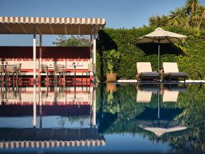 拉加纳斯仙人掌酒店的游泳池配有椅子、遮阳伞和桌子