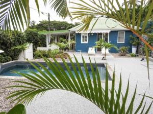 Case-PiloteComplexe de deux bungalows de standing的前面有棕榈树的蓝色房子