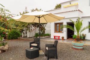 蓬塔利亚纳博迪哥古雅公寓的庭院配有遮阳伞、椅子和桌子。