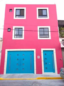 莱昂Casa Republik的前面有蓝色车库门的粉红色建筑