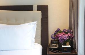 马尼拉马卡蒂钻石公寓式酒店的床头柜上一张带时钟和鲜花的床