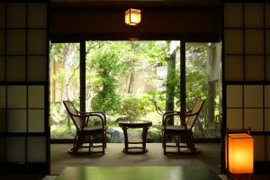 松本泉屋森贝酒店的窗户客房内的两把椅子和一张桌子