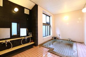 松本泉屋森贝酒店的大型浴室设有浴缸和淋浴。