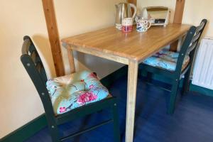 斯温福德The Cosy Cabin的一张桌子和两把椅子、一张木桌和一张桌子及椅子