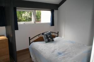 SchoorldamRekerlanden 14的一间卧室配有一张带枕头和窗户的床