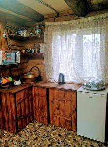 Novaya GreblyaКотедж ,,Чудовий"з банькою的厨房配有木制橱柜和窗户。