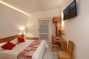希伯维列Hotel Restaurant 3 Châteaux的一间卧室配有一张床、一张书桌和一台电视