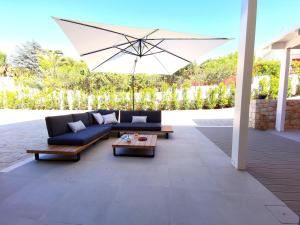 塞尔瓦迪法萨诺VILLA NUCCI by Apulia Hospitality的天井配有沙发、桌子和雨伞。