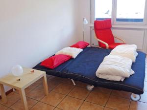 南达Apartment Valaisia 35A by Interhome的一张带枕头的床和一张红色椅子