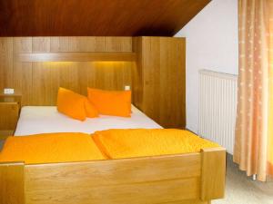 索尔登Apartment Alpenblick - SOE750 by Interhome的一间卧室配有带橙色枕头的木床