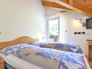 坎皮泰洛Apartment Cecilia-4 by Interhome的一间卧室配有一张带蓝色棉被的床和窗户。