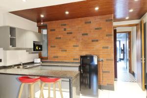 新德里Apt# ONE-FOUR-TWO - with Lift - High Speed Wifi - Smart TV的厨房设有2个吧台凳和砖墙