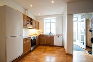 森讷堡Penthouse的厨房配有木制橱柜和白色冰箱。