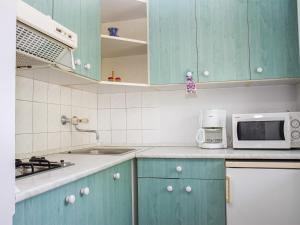 鲍洛通凯赖斯图尔Apartment Cortaderia 2 by Interhome的厨房配有蓝色橱柜和微波炉