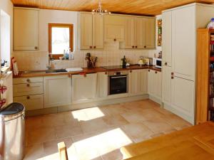 布拉滕Holiday Home Chalet Eden by Interhome的厨房配有白色橱柜和瓷砖地板。