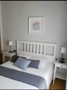 马拉加Málaga Centro的卧室配有一张白色床、两张桌子和两盏灯。
