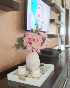 布德瓦Apartman Anja的花瓶,桌子上放着粉红色的花,有两杯
