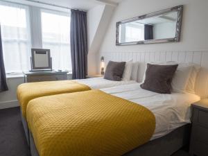 伊尔弗勒科姆卡尔顿酒店的一间卧室配有两张带黄毯的床