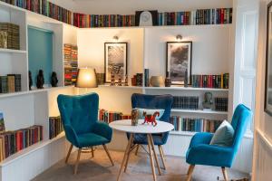伊尔弗勒科姆卡尔顿酒店的图书馆配有蓝色的椅子、桌子和书架